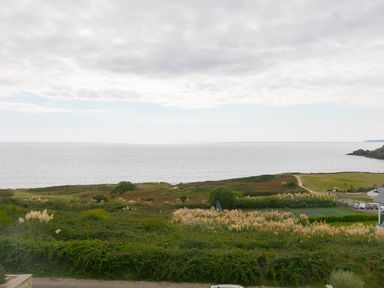 A coastal view with green vegetation and a tennis court near the sea at Sea Sands in Praa Sands