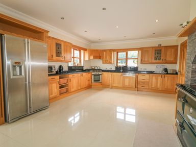A kitchen with wooden cabinets stainless steel refrigerator stove and windows at Redford View in Culdaff County Donegal