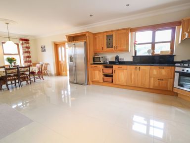 A kitchen with wooden cabinets stainless steel refrigerator and dining table with chairs at Redford View in Culdaff County Donegal