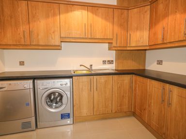 A kitchen with wooden cabinets a washing machine a dryer and a sink at Redford View in Culdaff County Donegal