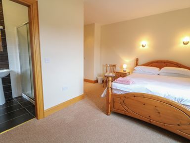A bedroom with a wooden bed and bedside table with lamp next to a bathroom at Redford View in Culdaff County Donegal