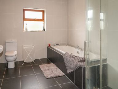 A bathroom with a bathtub a toilet a laundry basket and a window at Redford View in Culdaff County Donegal