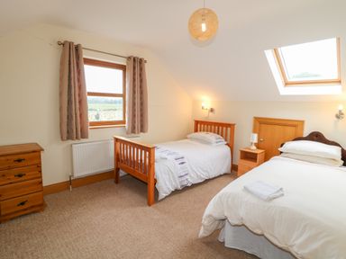 A bedroom with two single beds a wooden dresser and nightstand with a lamp at Redford View in Culdaff County Donegal