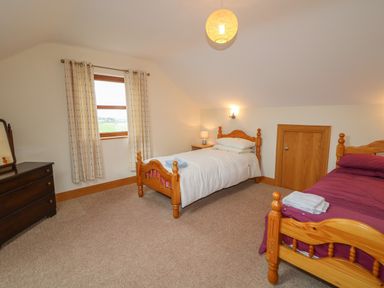 A bedroom with two single wooden beds a window with curtains and a dresser at Redford View in Culdaff County Donegal