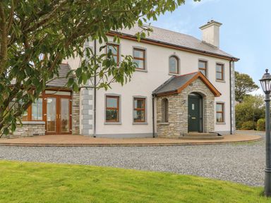 A two-story house with a stone porch and multiple windows with brown frames at Redford View in Culdaff County Donegal