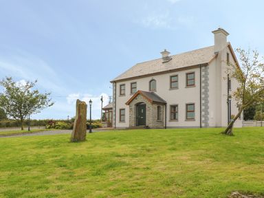 A two-story house with stone porch surrounded by grass and trees at Redford View in Culdaff County Donegal