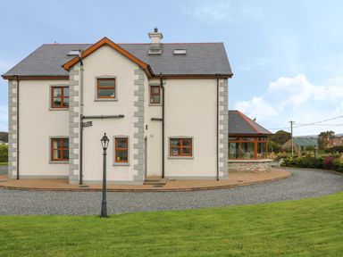 The exterior of a two story house with grey roof and brown framed windows surrounded by grass and a gravel driveway at Redford View in Culdaff County Donegal