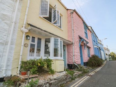 A row of colorful houses along a sloped street with plants outside at Pixie Cottage in Looe