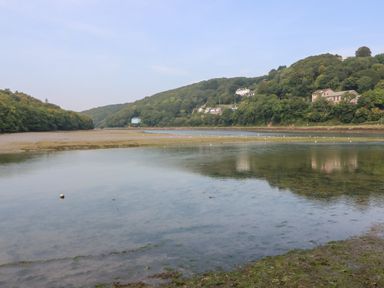 A river with vegetation on hills and houses along the shoreline at Pixie Cottage in Looe