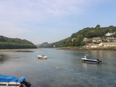 A river with boats on the water and houses on a hillside at Pixie Cottage in Looe