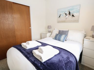 A bedroom with a bed covered by white and blue bedding and towels on top at 14 Siesta Mar in Mundesley