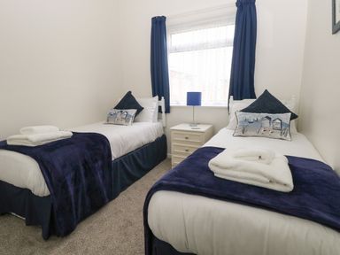 A bedroom with two single beds separated by a nightstand with a lamp at 14 Siesta Mar in Mundesley