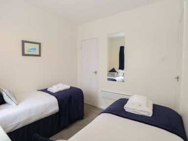 A bedroom with two single beds with folded towels on each bed and a wall mirror at 14 Siesta Mar in Mundesley