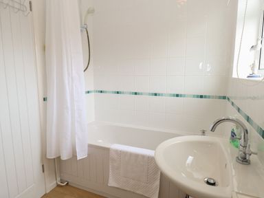 A bathroom with a bathtub shower curtain sink and faucet at 14 Siesta Mar in Mundesley