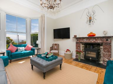 A living room with sofas a fireplace a wall mounted television and large windows at 6 Albany Terrace in St Ives