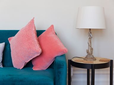 A teal sofa with pink cushions next to a side table with a lamp at 6 Albany Terrace in St Ives