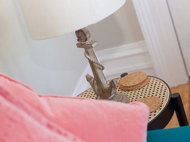 A side table with a nautical-themed lamp and cork coasters beside a pink cushion at 6 Albany Terrace in St Ives
