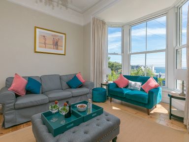 A living room with two sofas cushions a large window and a coffee table at 6 Albany Terrace in St Ives