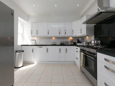 A kitchen with white cabinets stainless steel appliances and tiled floor at 6 Albany Terrace in St Ives