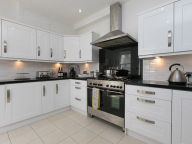A kitchen with white cabinets a stainless steel stove kettle and countertop appliances at 6 Albany Terrace in St Ives