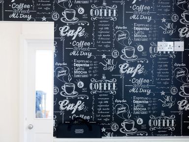 Wall with coffee-themed black and white chalkboard style wallpaper and a white door with a glass panel at 6 Albany Terrace in St Ives