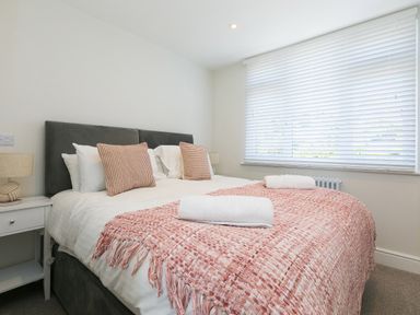 A bedroom with a double bed white bedside tables and a window with blinds at 6 Albany Terrace in St Ives