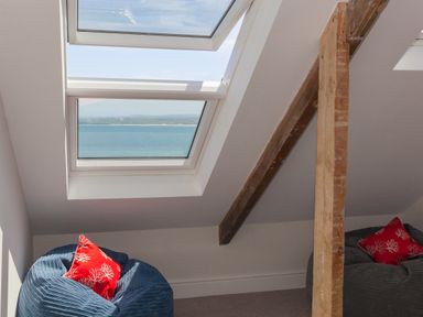A room with skylight windows showing a sea view two bean bag chairs with red cushions and a wooden beam in 6 Albany Terrace St Ives