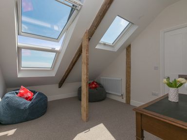 An attic room with skylight windows two bean bag chairs and a wooden desk with flowers at 6 Albany Terrace in St Ives