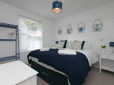 A bedroom with a double bed navy bedding and white furniture at 6 Albany Terrace in St Ives