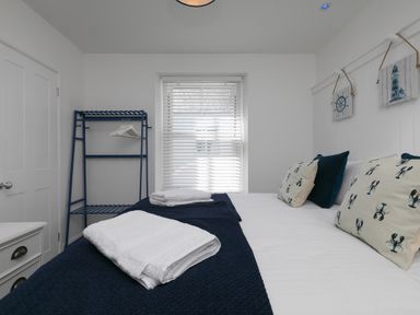 A bedroom with a bed and towels on it a window and a clothes rack at 6 Albany Terrace in St Ives