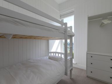 A bedroom with bunk beds a window and a dresser with hangers at 6 Albany Terrace in St Ives