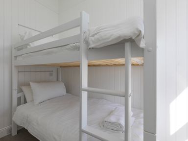 A bedroom with a white bunk bed and towels on the lower bed at 6 Albany Terrace in St Ives
