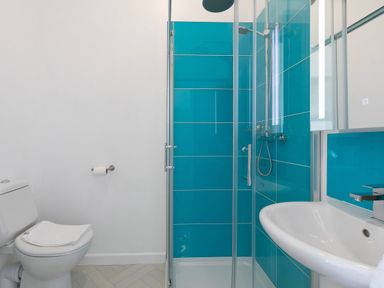 A bathroom with a toilet sink and glass shower with blue tiled walls at 6 Albany Terrace in St Ives