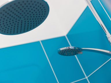 A shower area with a rain shower head and a handheld shower head on blue tiled walls at 6 Albany Terrace in St Ives