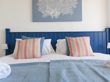 A bed with striped and blue pillows a blue headboard and a blue blanket at 6 Albany Terrace in St Ives