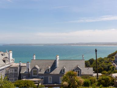 A coastal view with buildings in the foreground and the sea with distant land in the background at 6 Albany Terrace in St Ives