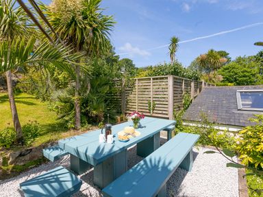 An outdoor seating area with a blue wooden table and benches surrounded by plants at 6 Albany Terrace in St Ives