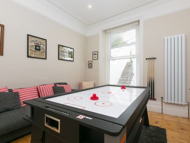 A game room with an air hockey table a sofa with striped cushions and wall art at 6 Albany Terrace in St Ives