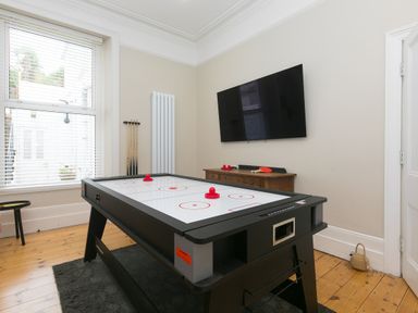 A game room with an air hockey table and a large TV mounted on the wall at 6 Albany Terrace in St Ives