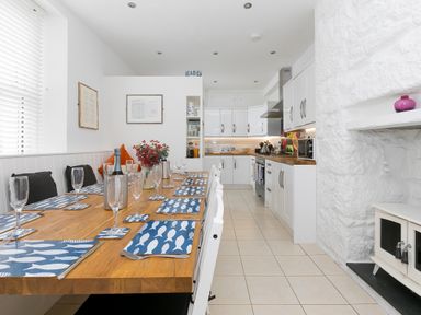 A kitchen with a wooden dining table set with placemats and glasses at 6 Albany Terrace in St Ives