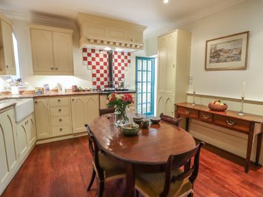 A kitchen with cream cabinets a wooden dining table with chairs and a sideboard at Lion House in Moretonhampstead
