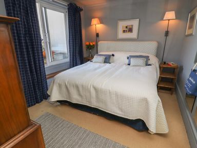 A bedroom with a double bed two bedside tables and lamps a window with curtains and a wooden dresser at Lion House in Moretonhampstead