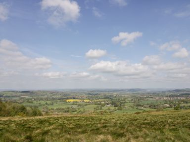 A wide landscape view of fields trees and distant houses under a blue sky with clouds at Tor Cottage in Colwall Herefordshire