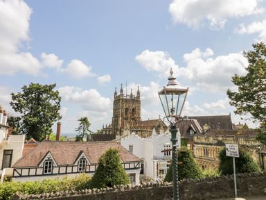 A townscape with a church tower lamp post and road sign at Tor Cottage in Colwall Herefordshire