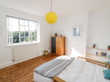 A bedroom with a bed a wooden cabinet a window and two shelves on the wall at Tor Cottage in Colwall Herefordshire