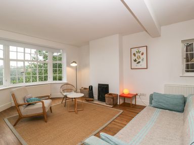 A living room with armchairs a sofa a small round table a floor lamp and a large window at Tor Cottage in Colwall Herefordshire