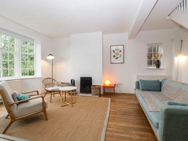 A living room with a blue sofa and armchairs around a coffee table and a window at Tor Cottage in Colwall Herefordshire