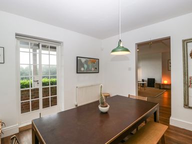A dining room with a dark table and cactus plant a green pendant light and large window at Tor Cottage in Colwall Herefordshire