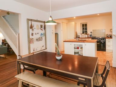 A kitchen with an island and dining table with chairs and a bench at Tor Cottage in Colwall Herefordshire