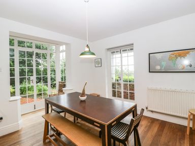 A dining room with a table bench and chairs near glass doors and a wall map at Tor Cottage in Colwall Herefordshire